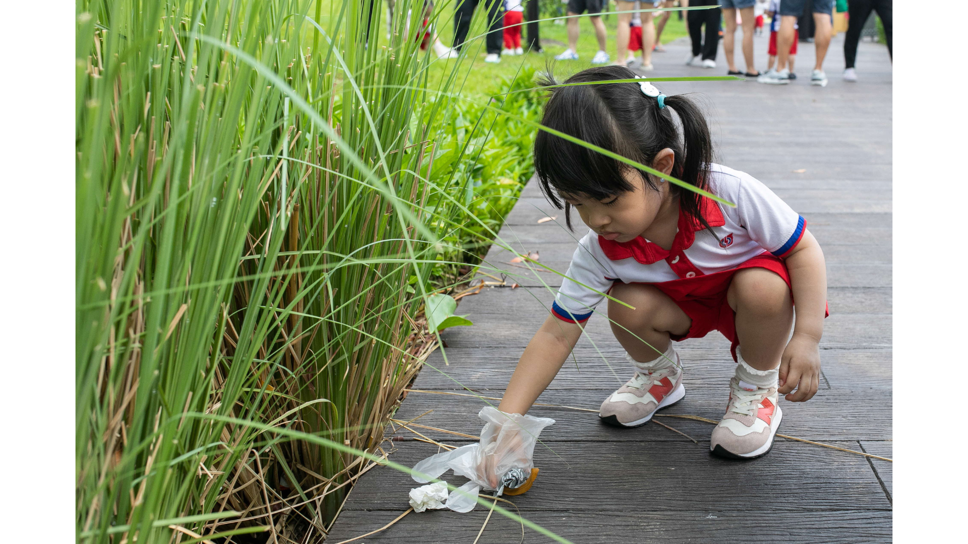 young girl picks up litter with a glove